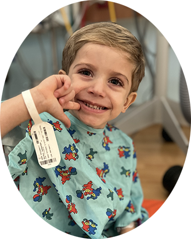 A small boy wears a cpap mask in a hospital bed. he is holding someone's hand.